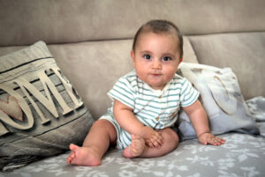 Petit bébé assis, pieds nus, regarde le photographe