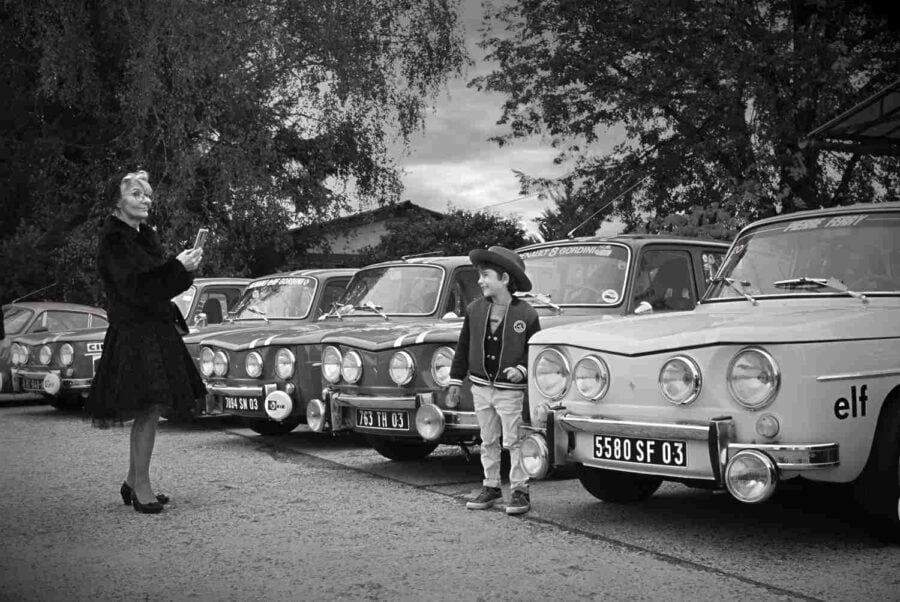 petit garçon qui se fait photographier au milieu de vieilles voitures de rallye